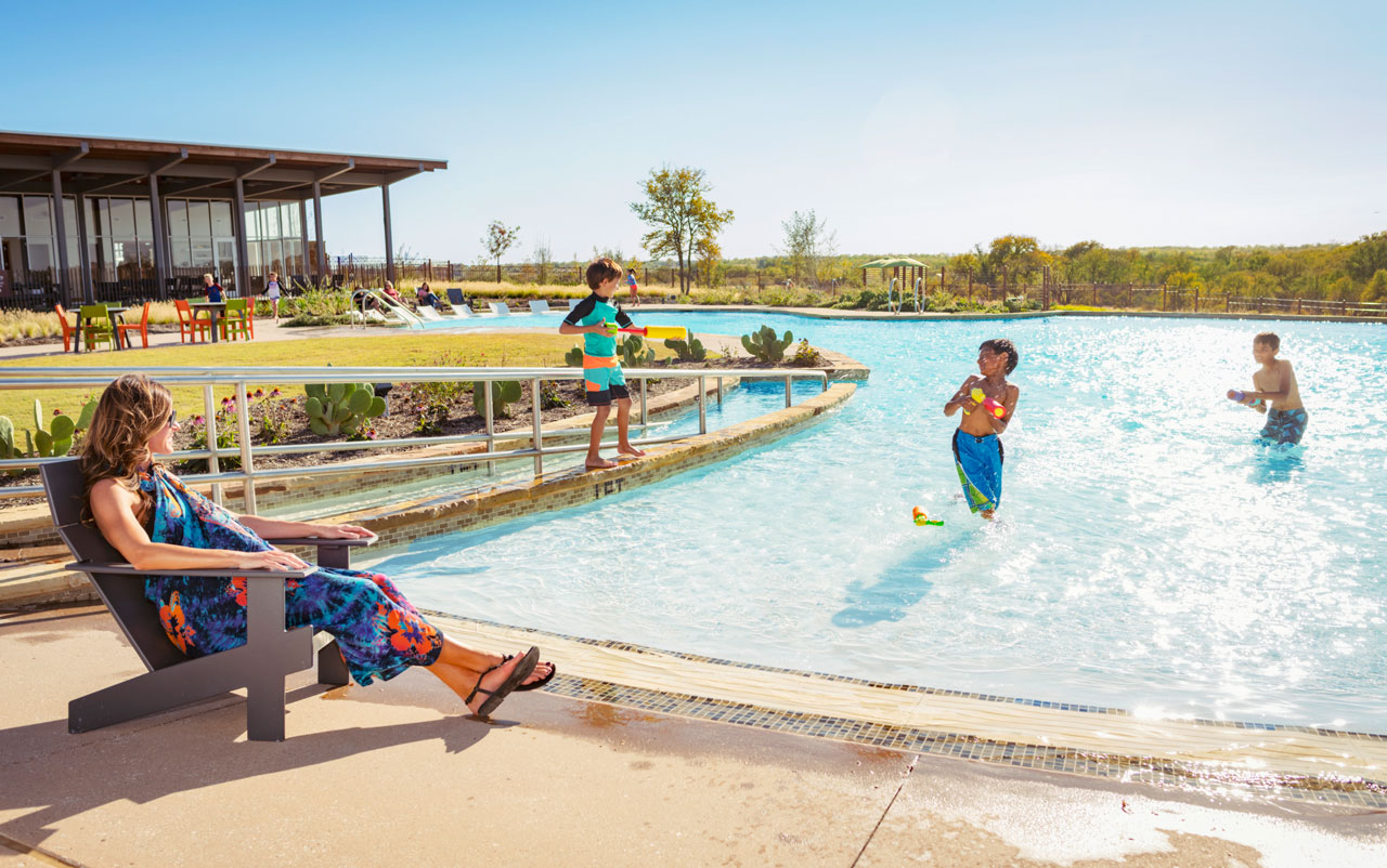 Three boys playing in Canyon Falls community pool with mom watching