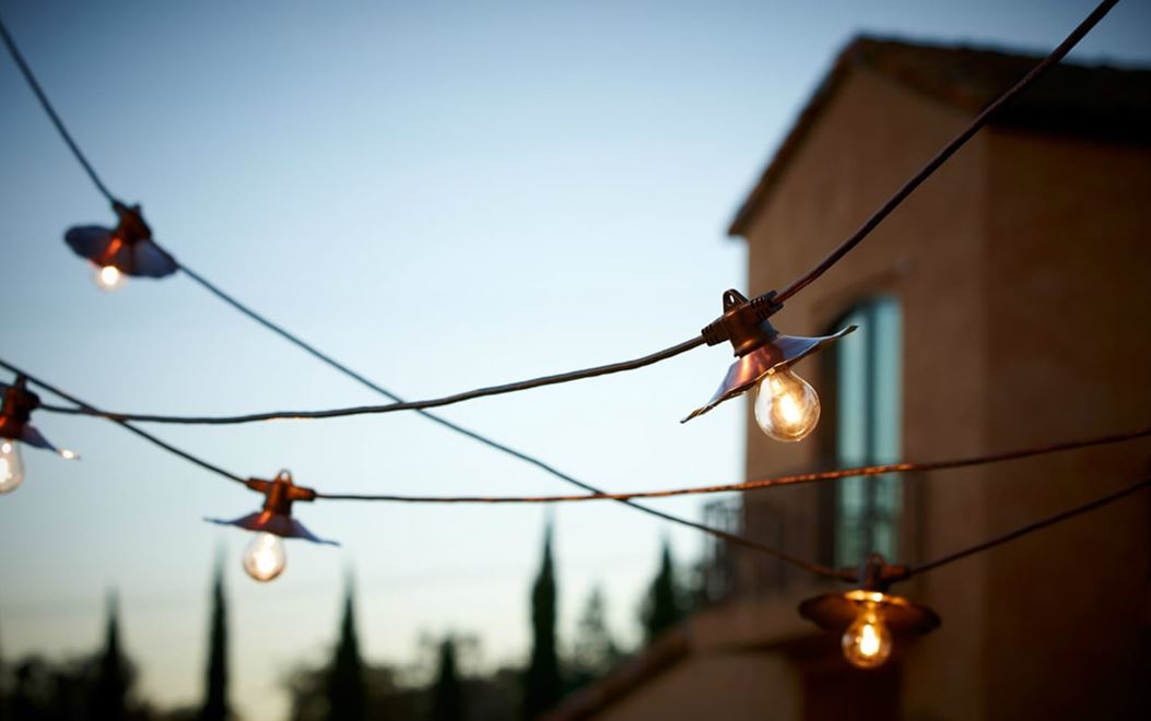 A string of overhead outdoor lights at dusk