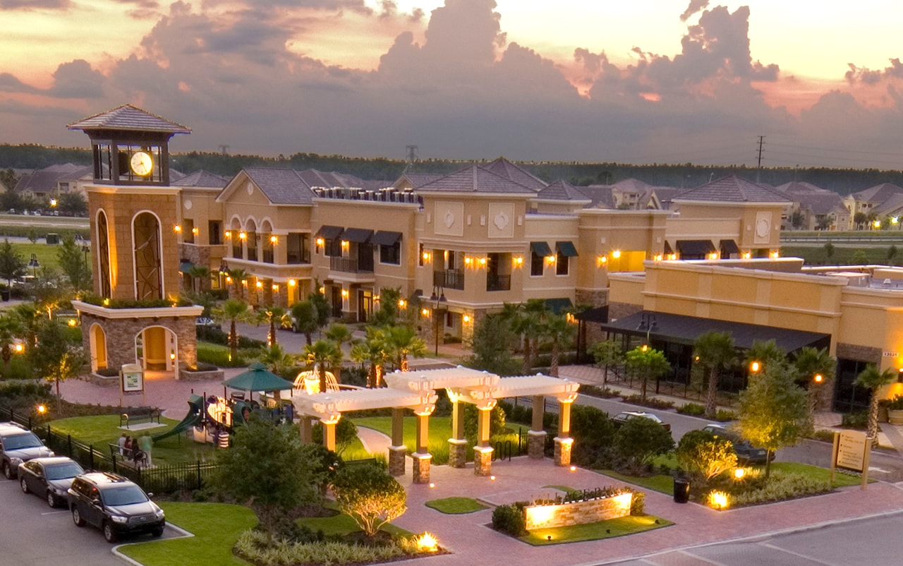 Exterior of a commercial retail center at dusk with lights on