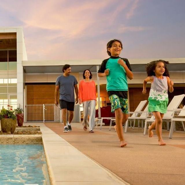 Family of four walking alongside hollyhock community pool