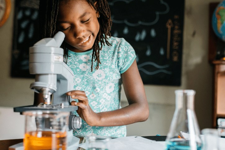 Young girl looking through a microscope at school