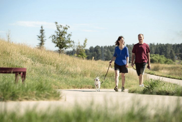 Couple walking dog on a suburban trail