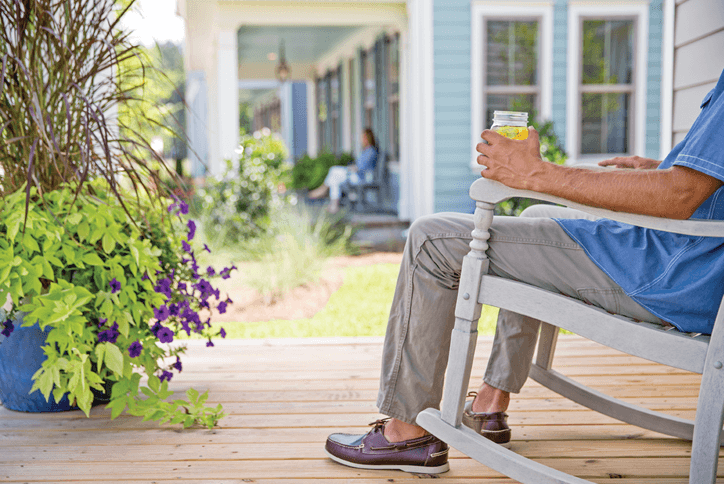 Man in a rocking chair enjoying iced tea on a front porch